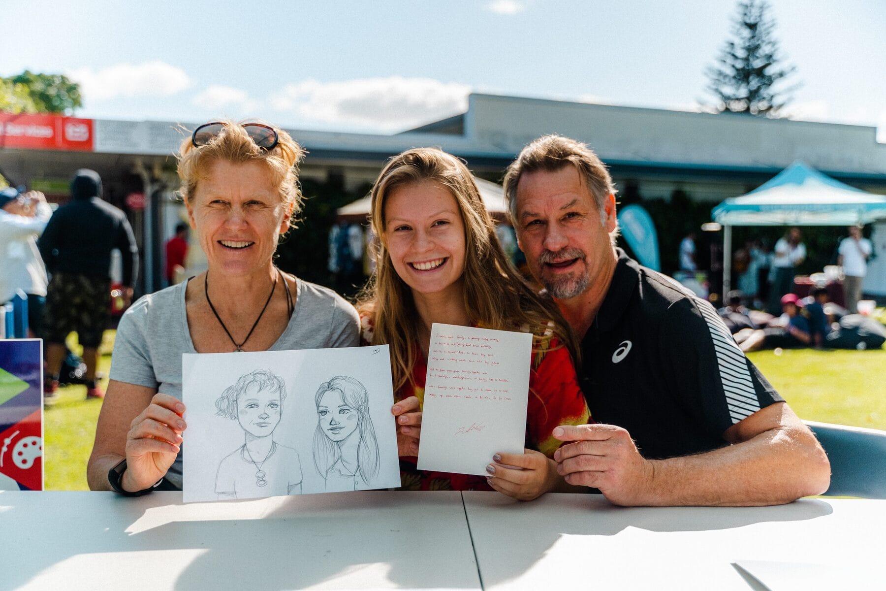 A family holding up the portraits drawn for them