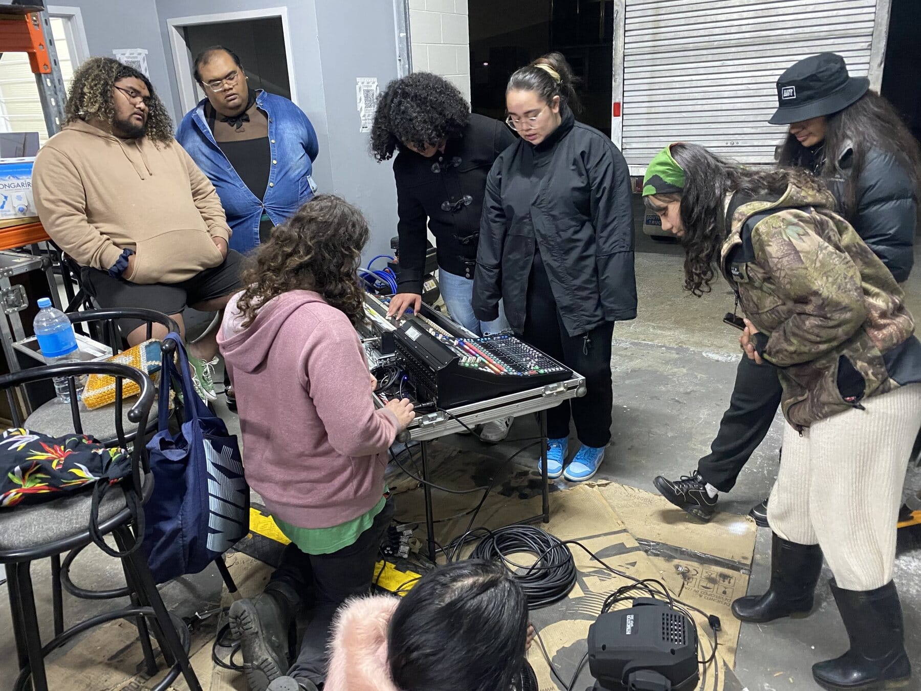 Young crew gathered round a mixing desk learning to run sound