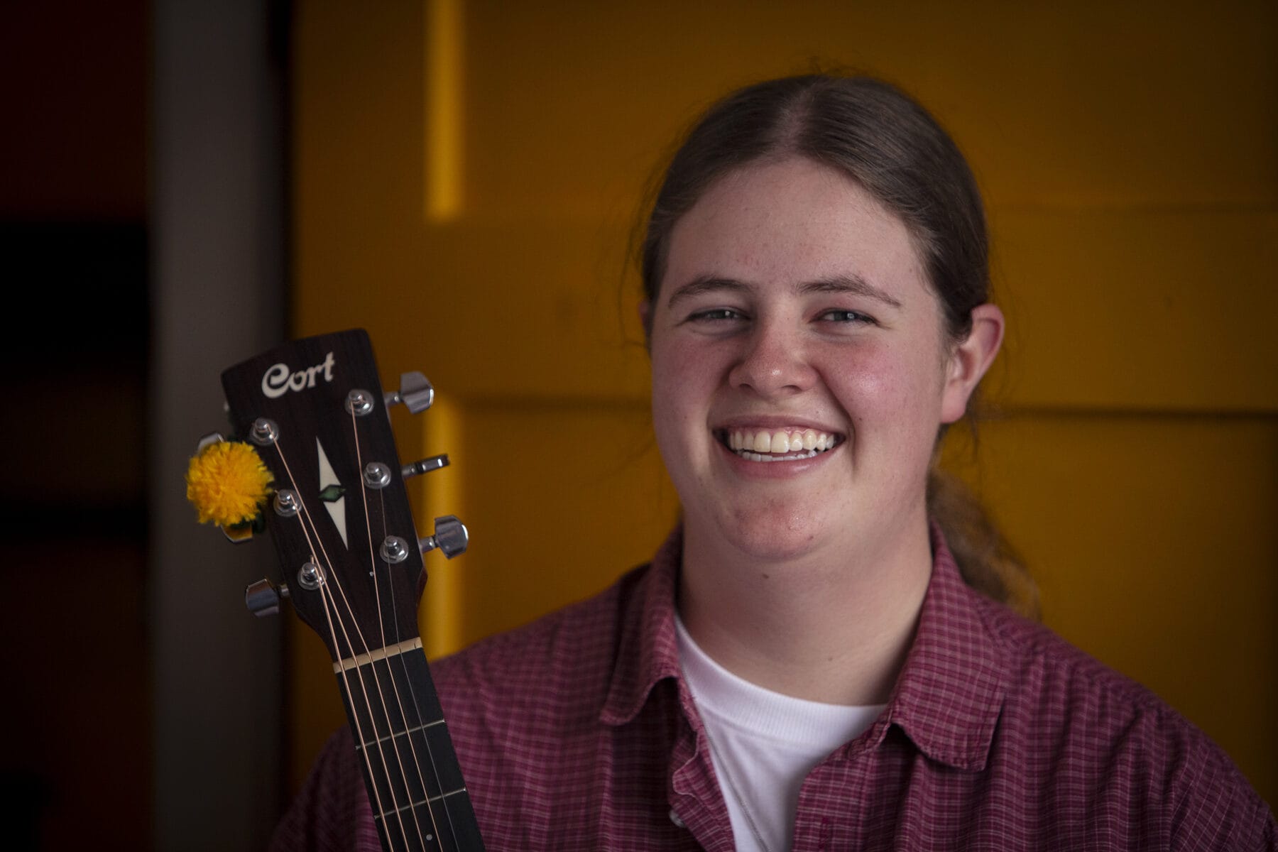 A first-time performer smiling with her guitar