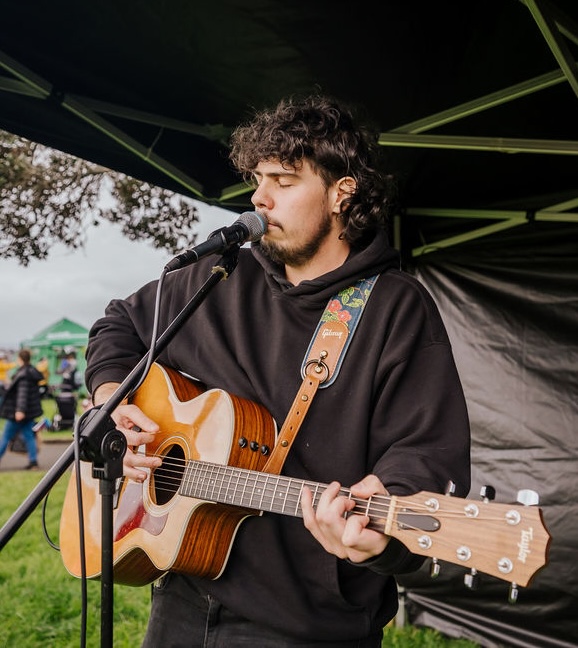 Young musician playing guitar and singing on stage